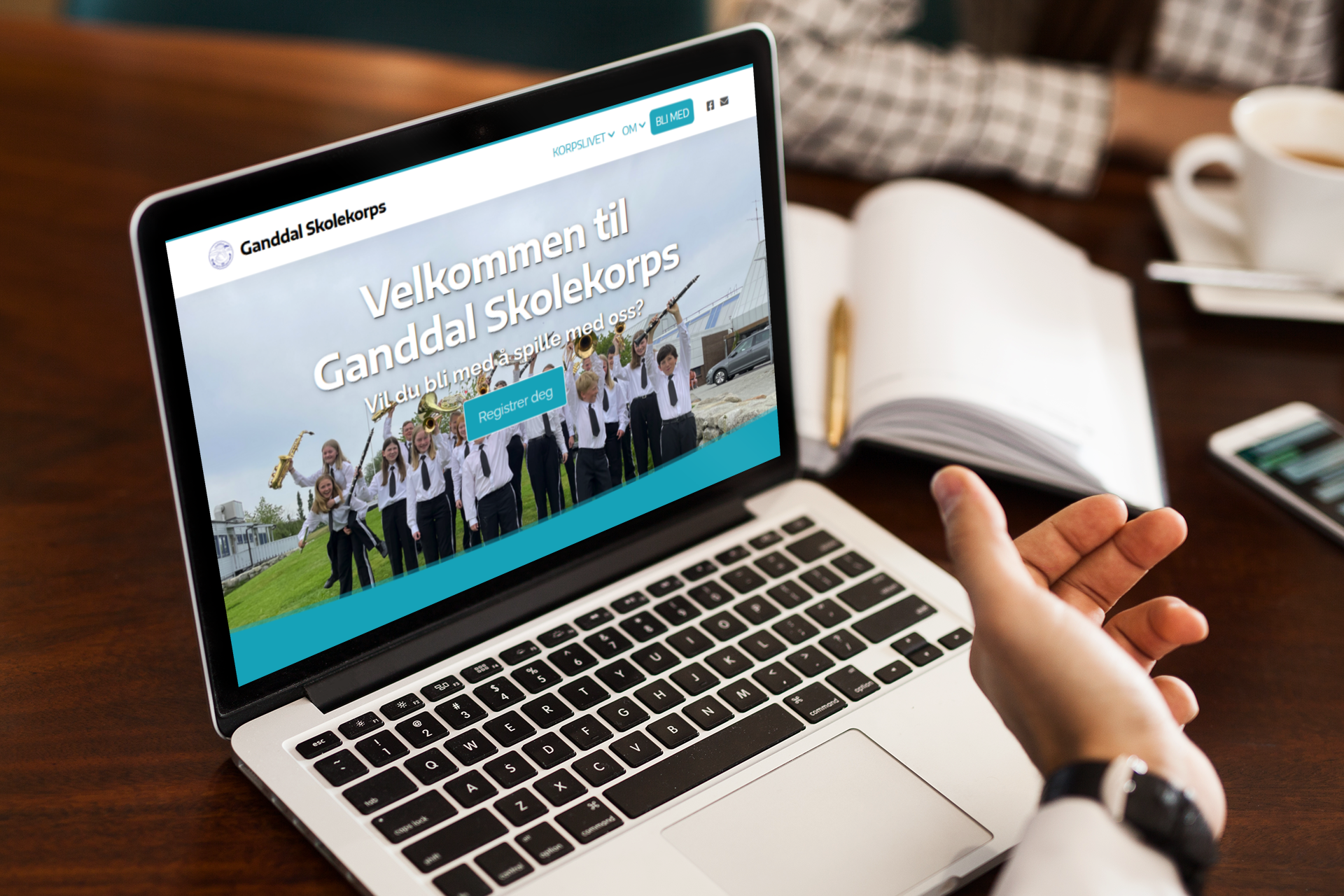 Nettside Bærbar PC som viser illustrasjonsbilde av en nettside. Tekst på nettsiden "Velkommen til Ganndal Skolekorps"